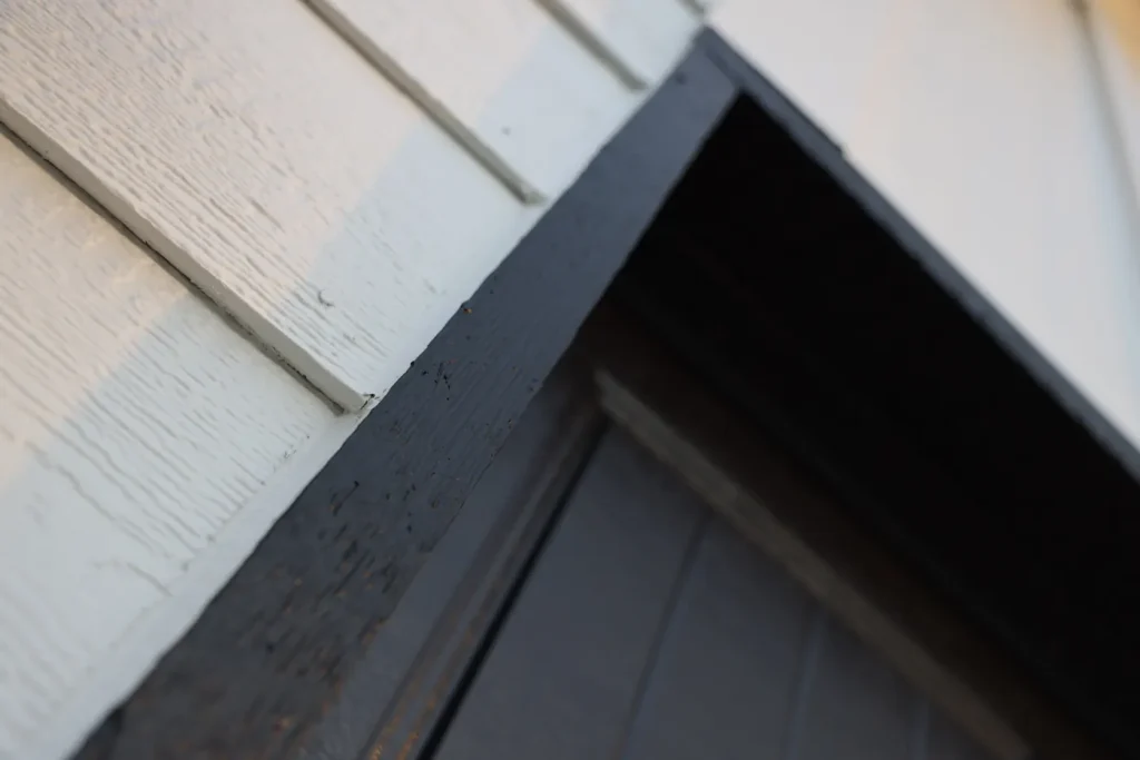 Close-up of charcoal-painted wood trim beside white siding.