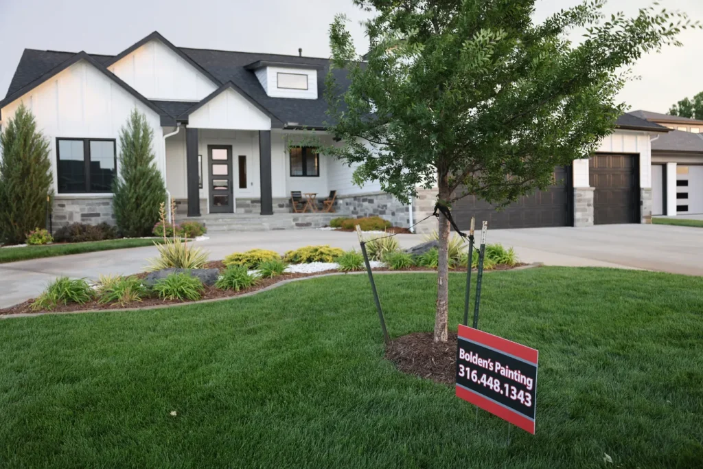 White house with charcoal trim and a Bolden’s Painting yard sign.